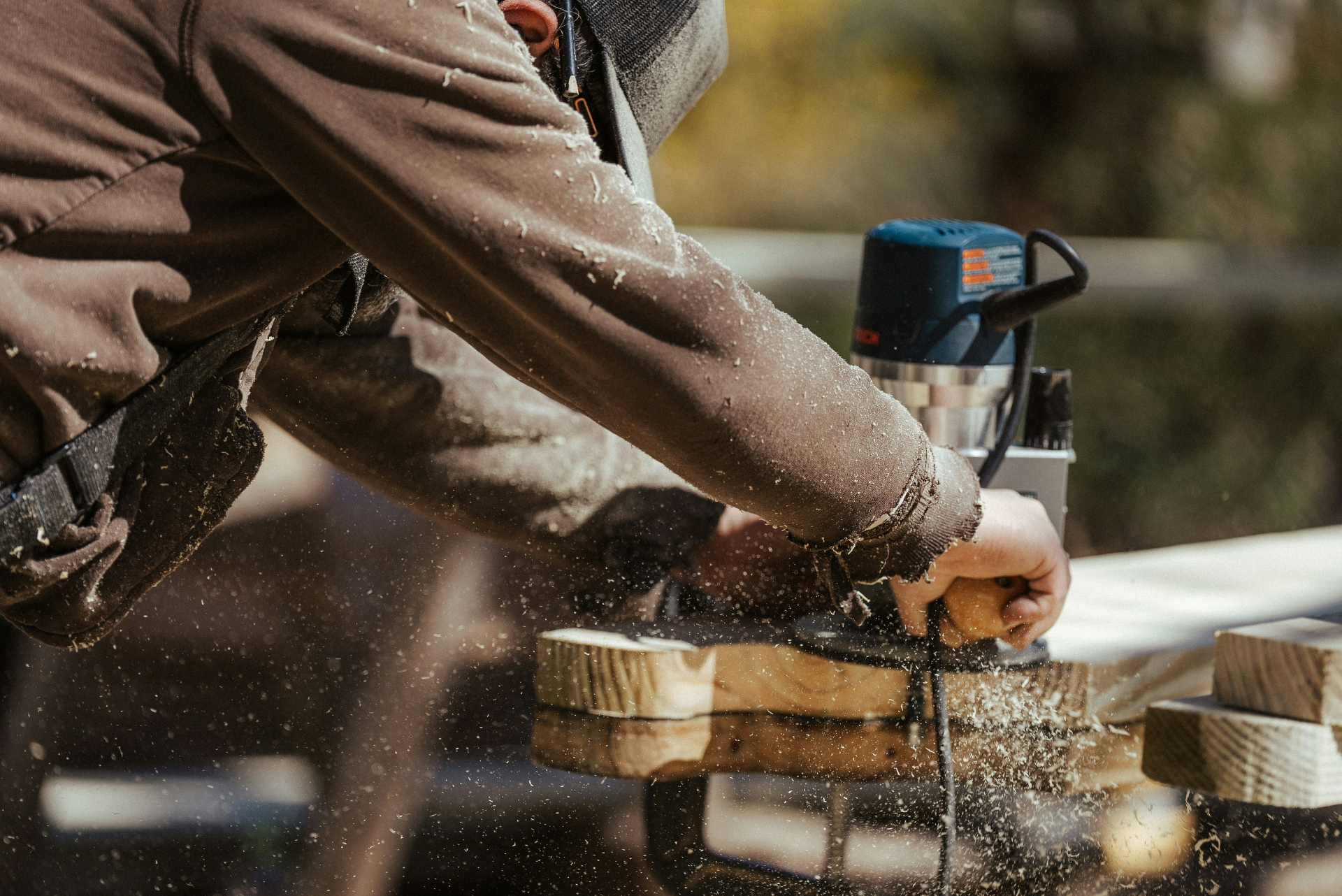 Craftsman using router on custom woodwork with sawdust in the air